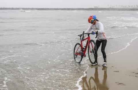 Isabella dips her bike into the Pacific Ocean at the start of her cross-country bike ride