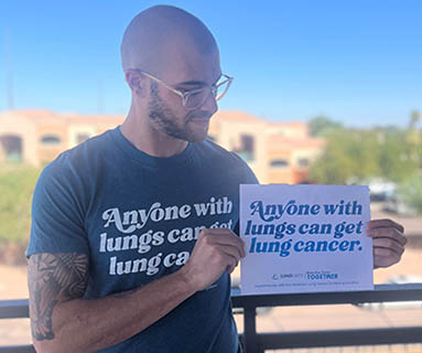 Person holding an "Anyone with Lungs" sign