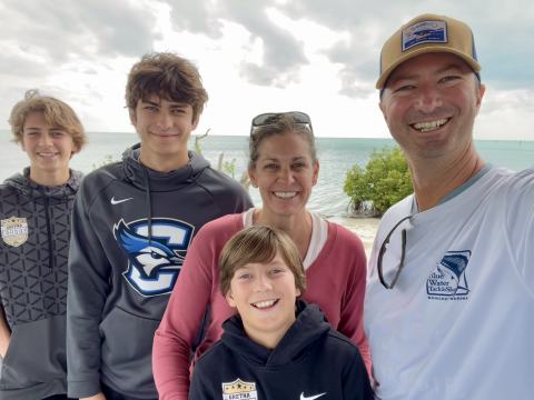 Man (Frank) smiling with his wife and three sons with water in the background