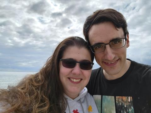 Woman and husband smiling at camera with clouds and water in background